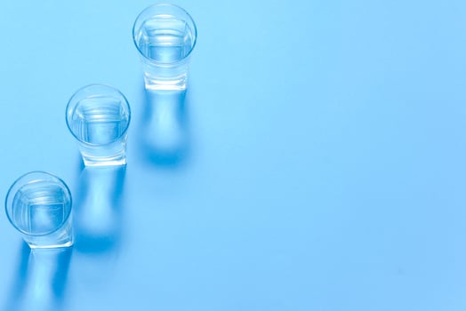 Glasses of water on blue. Close up. Copy space. Water balance for healthy and detox. photo