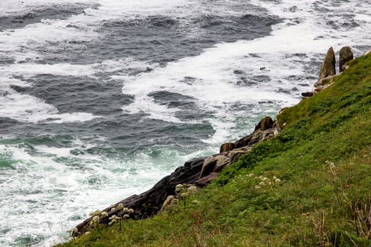 Rough Seas Crashing Against Green Cliffs on a Cloudy Day, in Ireland photo