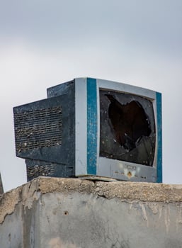 A Broken Television Abandoned on a Concrete Wall photo