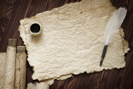 white feather and ancient scroll on brown plank photo