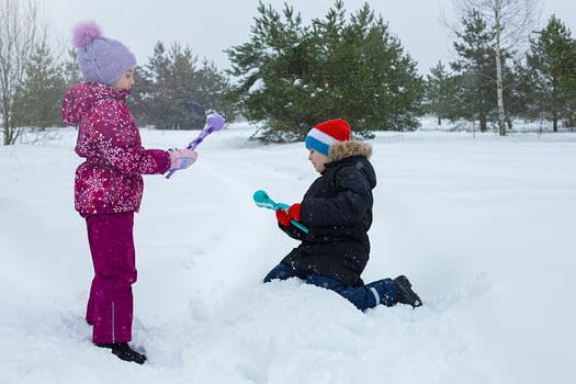 A boy and a girl are outdoors in winter, making snowballs with plastic sculpting tools. photo