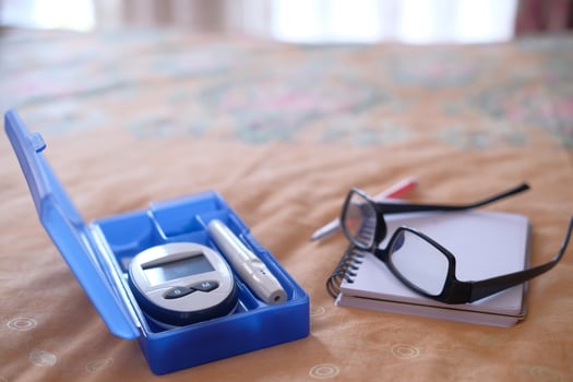 diabetic measurement tools and eyeglass on bed photo