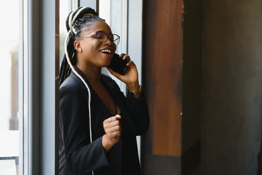 smiling black woman talking on the phone while resting in a cafeteria, selective focus photo