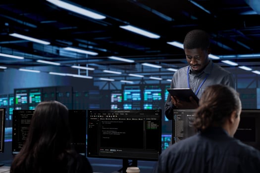 Multiethnic team in server room checking recovery plan and monitoring energy consumption. Diverse group of employees in data center location doing routine disk checks across components photo