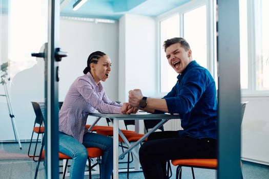 In a modern startup office, a businessman and a businesswoman business colleagues engage in a symbolic arm-wrestling match, reflecting teamwork, competition, and innovation in their dynamic workplace. photo