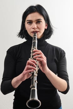 Graceful Brunette Musician Posing with Clarinet on White Background photo