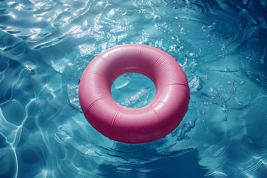 A pink inflatable ring floats in a sparkling blue swimming pool photo