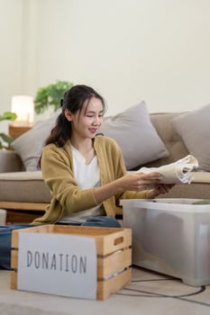 Volunteer Sorting and Donation Clothes for Charity in a Modern Living Room Setting, Promoting Community Support and Generosity photo