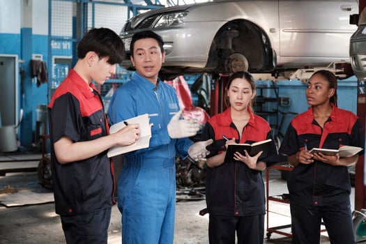 Specialist lecture. Male supervisor engineer describe automotive suspension fixing with mechanic worker staff teams for repair work at car service garage and maintenance jobs in automobile industry. photo