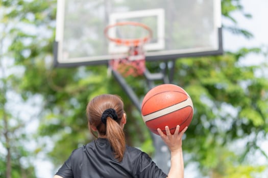 Back view of active Asian woman playing basketball in the urban outdoor basketball court, Healthy life concepts photo