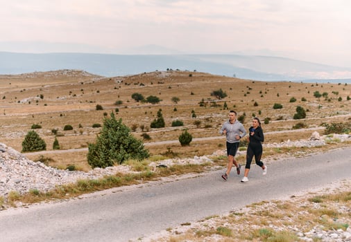 A couple dressed in sportswear runs along a scenic road during an early morning workout, enjoying the fresh air and maintaining a healthy lifestyle photo
