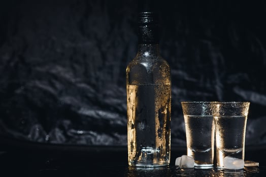 Close-up view of bottle of vodka with glasses standing on ice on black. photo