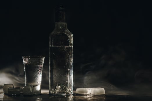 Vodka shots with ice on black table, copy space. photo