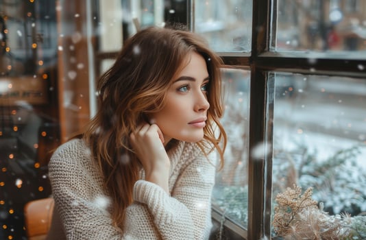 Woman Looking Out Window at Winter Scene photo