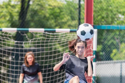 Mom with a child playing football in the urban outdoor futsal court photo