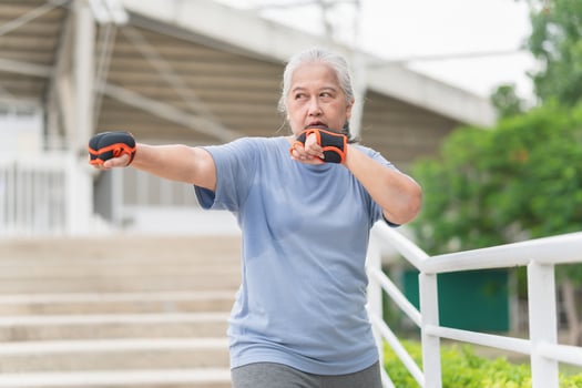 Asian senior sportswoman boxing while working out on parking outdoors photo