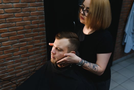 Client during beard shaving in barber shop photo