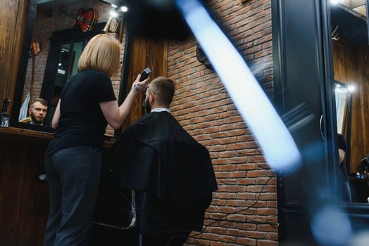 Barber Woman Cutting Man Hair at the Barbershop. Woman Working as a Hairdresser. Small Business Concept. photo
