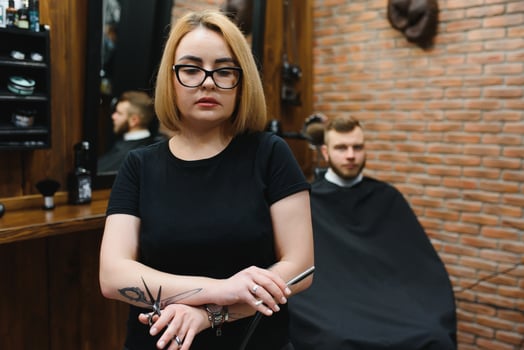 Portrait of fashion woman barber hairstylist with scissors in hand in the barbershop photo