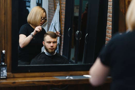 Barber Woman Cutting Man Hair at the Barbershop. Woman Working as a Hairdresser. Small Business Concept. photo