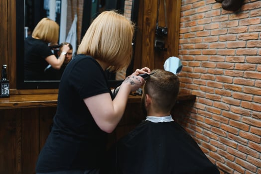 Barber Woman Cutting Man Hair at the Barbershop. Woman Working as a Hairdresser. Small Business Concept. photo
