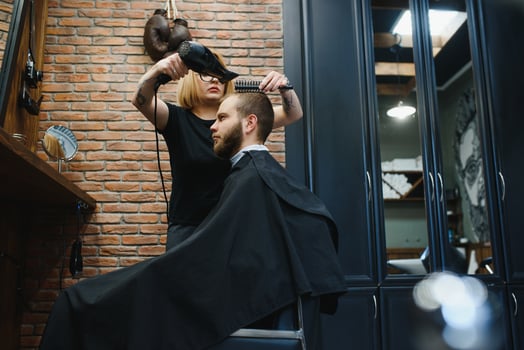 Stylish man sitting barber shop Hairstylist Hairdresser Woman cutting his hair Portrait handsome happy young bearded caucasian guy getting trendy haircut Attractive barber girl working serving client photo