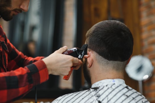 Barber shop. Man with wife in barber's chair, hairdresser Barbershop styling his hair. photo