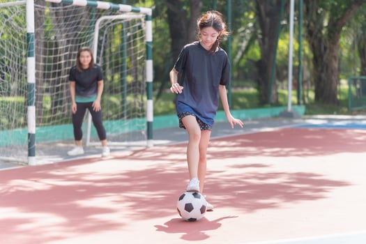 Mom with a child playing football in the urban outdoor futsal court photo