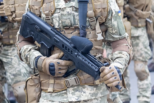A military man in camouflage uniform with an automatic rifle and the insignia of the Ukrainian army photo