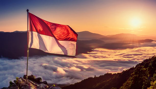 Indonesian Flag Waving Over a Sea of Clouds at Sunset photo