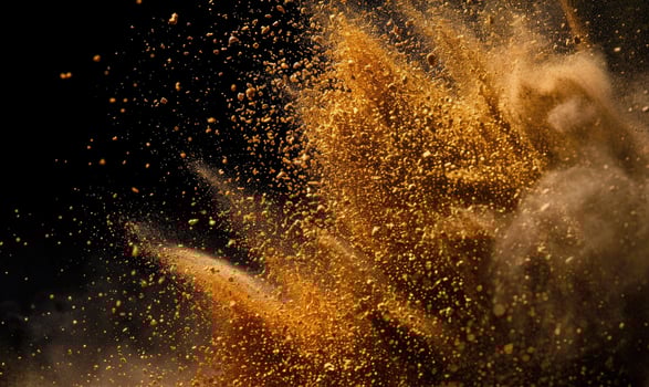 Sand explosion, golden grains dispersing on black background photo