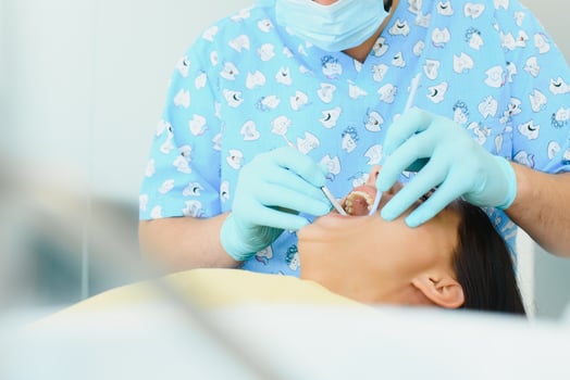 Midsection of male dentist adjusting apron on female patient before treatment in clinic photo