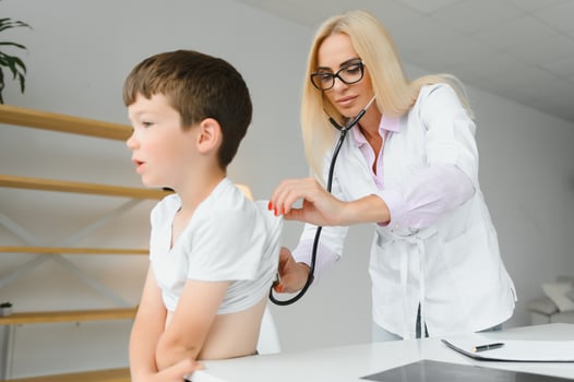 Female doctor examining boy by stethoscope photo