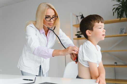 Doctor pediatrician examines child. Female doctor puts a stethoscope to a child's chest and listens to the little boy's heartbeat and lungs. Concept of health care and pediatric medical examination. photo