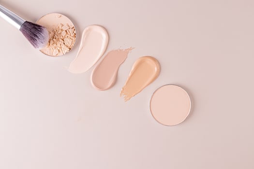 Three swatches of liquid foundation powder, two blocks of compact powder, a chic brush for applying powder. top view. Beauty and care concept photo