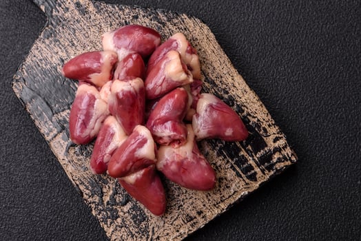 Raw chicken hearts with salt, spices and herbs photo