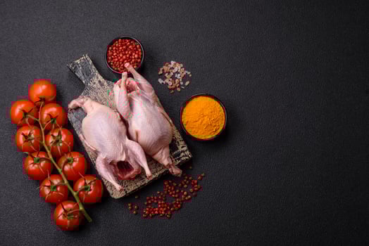 Whole raw quails with salt, spices and herbs on a dark concrete background photo