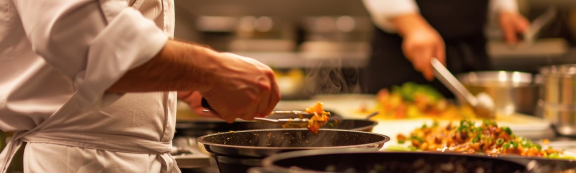 Chef preparing food in a kitchen with other cooks in the background, cooking class photo