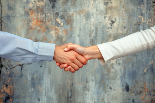Two people shaking hands in front of a rusty wall photo