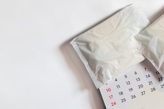 White sanitary napkin and calendar on a white background. Menstrual calendar concept with copy space. photo