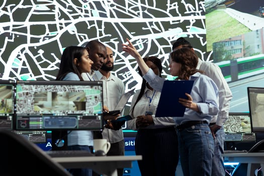 Group of diverse employees uniting forces to ensure express delivery, working on new routes to avoid urban traffic. Agency operating on CCTV surveillance system and satellite map tracking. photo