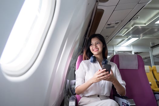 Business Woman Traveling on Airplane, Smiling Professional Female with Smartphone and Headphones, Modern Air Travel, Comfortable Seating, In Flight Experience, Corporate Travel, Business Trip photo