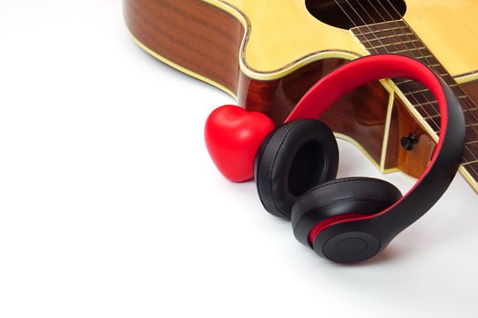 Acoustic guitar, headphones and red heart on a white background. Love, entertainment and music concept. photo