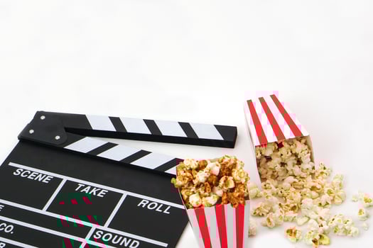 Clapperboard or movie slate black color with popcorn on white background. Cinema industry, production and film concept. photo