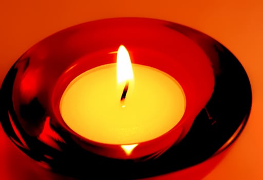 Burning candle close-up on red background photo