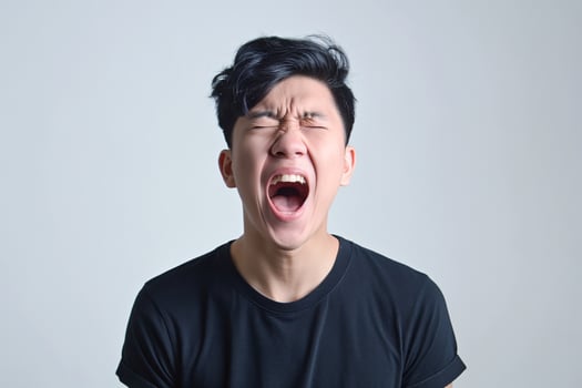 Young Asian Man Screaming in Frustration Wearing Black T-shirt in Studio photo