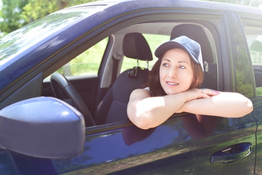 a portrait of a smiling woman wears hat sitting in the car, and looks aside photo