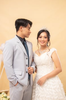 elegant couple man and woman standing poses formal relaxed smiling wide-eyed cheerful man hands focus on woman intimately indoor photo shot closeup. couple wedding national bride studio