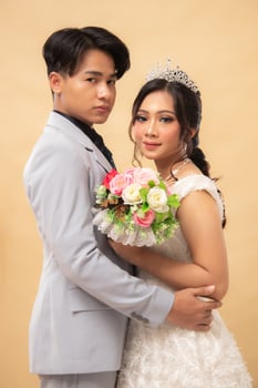 elegant couple man and woman standing pose relaxed smiling slightly looking forward man's hand hold woman's hand intimately indoor photo shot. couple wedding national bride studio