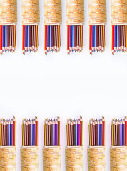 Colored pencils in a handmade birch bark organiser on white background. photo